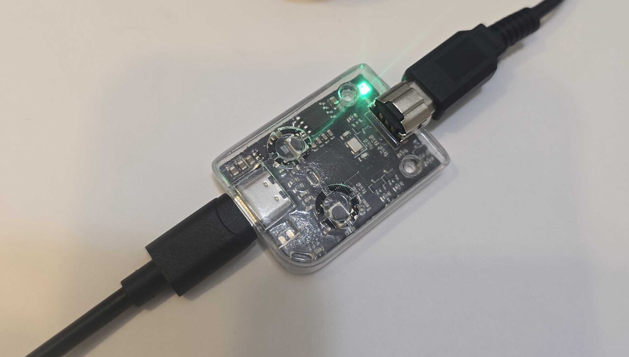 Top-down view of the clear-resin GB-Link adapter with USB-C and link cables attached