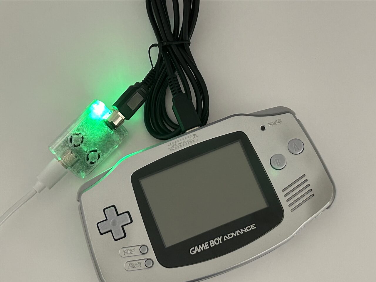GB-Link adapter connected to a silver Game Boy Advance by the link cable, its status LED glowing green