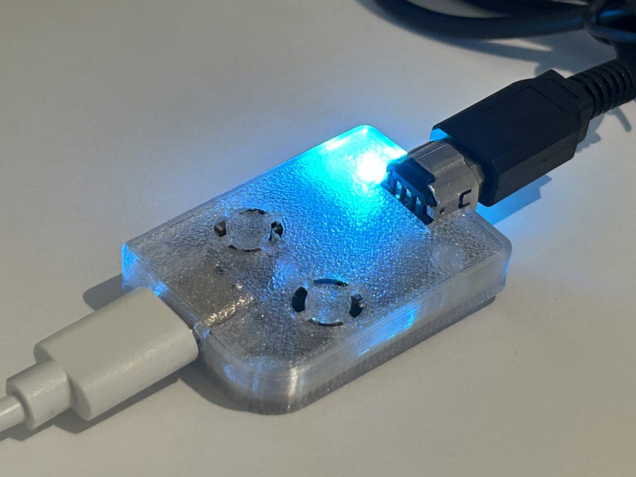 Close-up of the GB-Link adapter in its clear resin case, status LED lit blue